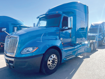 Blue 2020 International LT series sleeper truck parked, side view showing cab and front wheel.