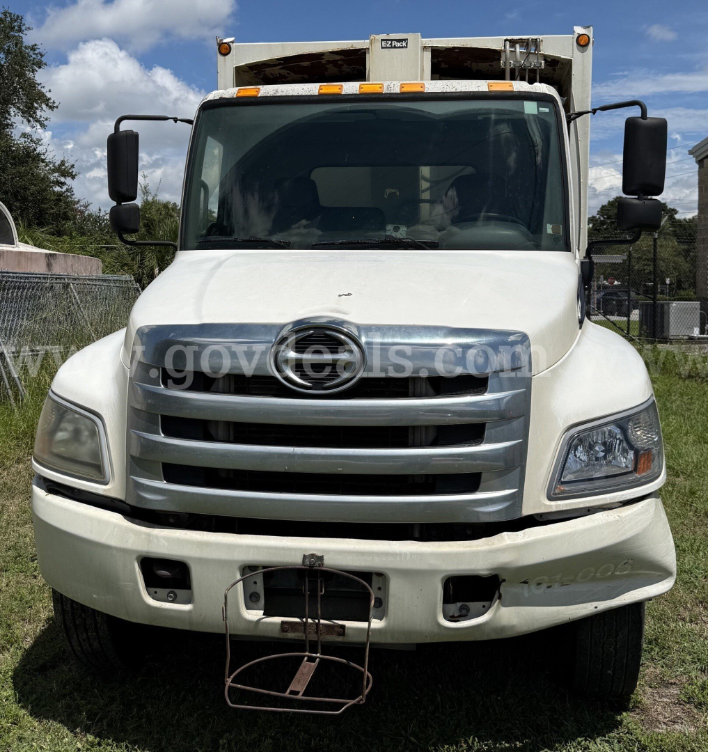 Front view of 2015 Hino 338 dump truck showing large chrome grille, headlights, and bumper.