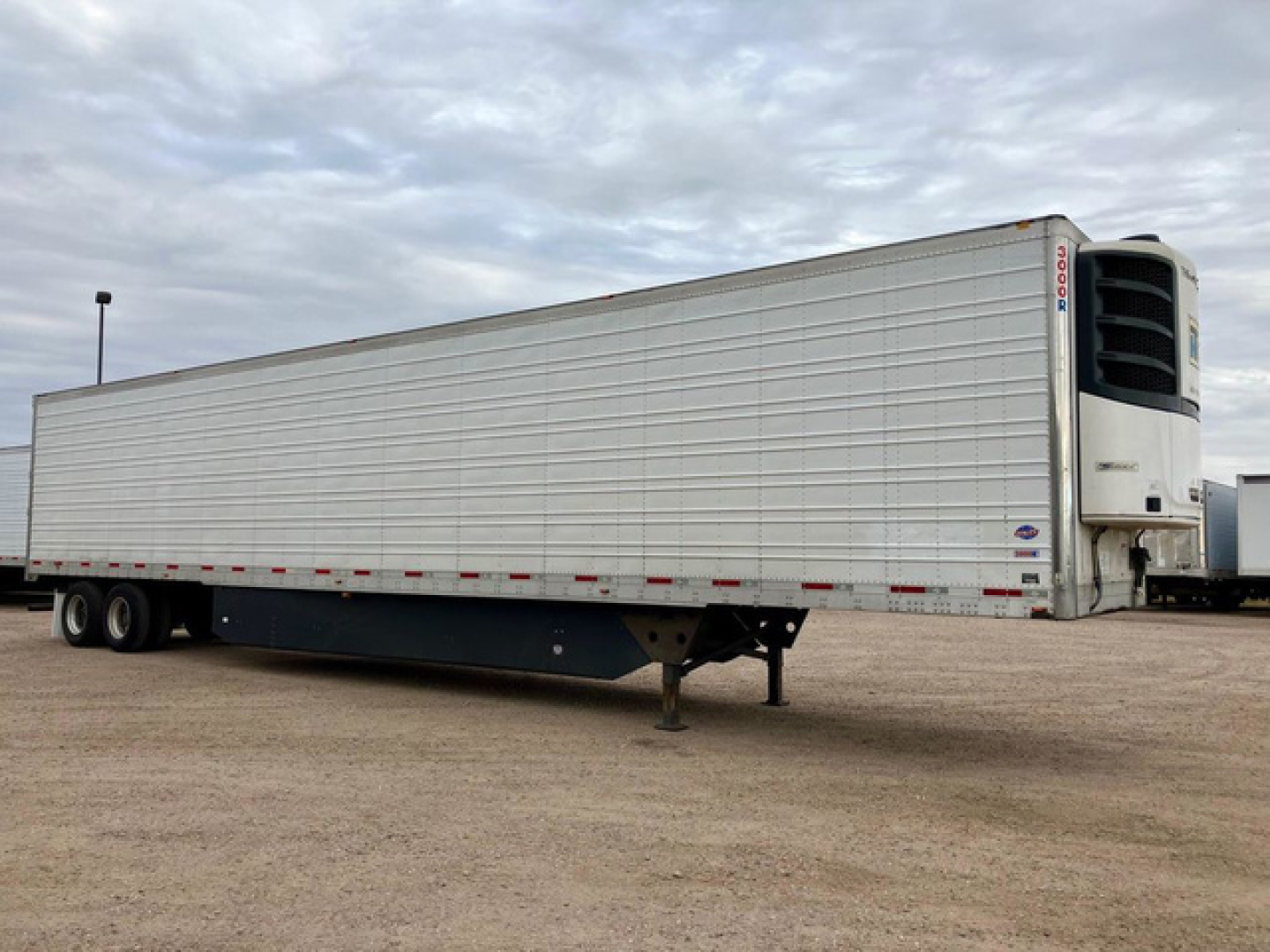 Trailer side view of a 2020 Utility reefer, refrigerated semi-trailer with Thermo King unit at front, white panel siding, aluminum wheels, tandem axles, landing gear, stock U90714.