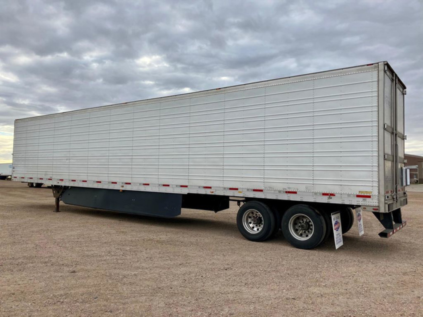 Utility reefer trailer side view showing tandem axle wheels and cooling unit in rear, aluminum exterior, stock U90714