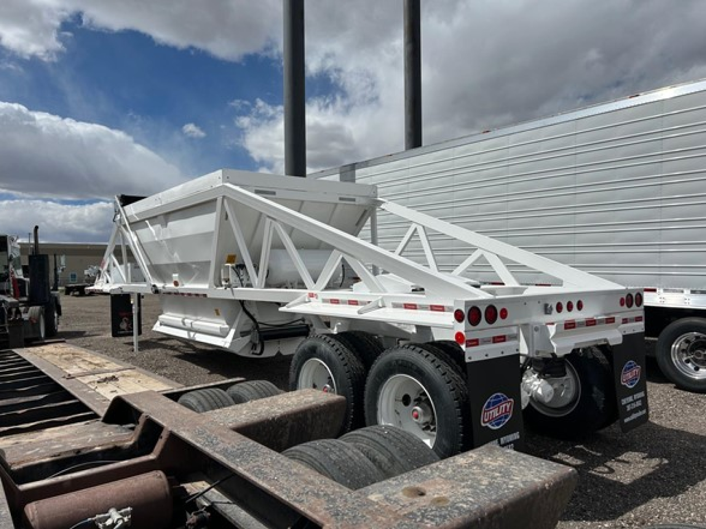 Trailer rear view showing a white Ranco air ride bottom dump trailer with multiple axles and black tires.