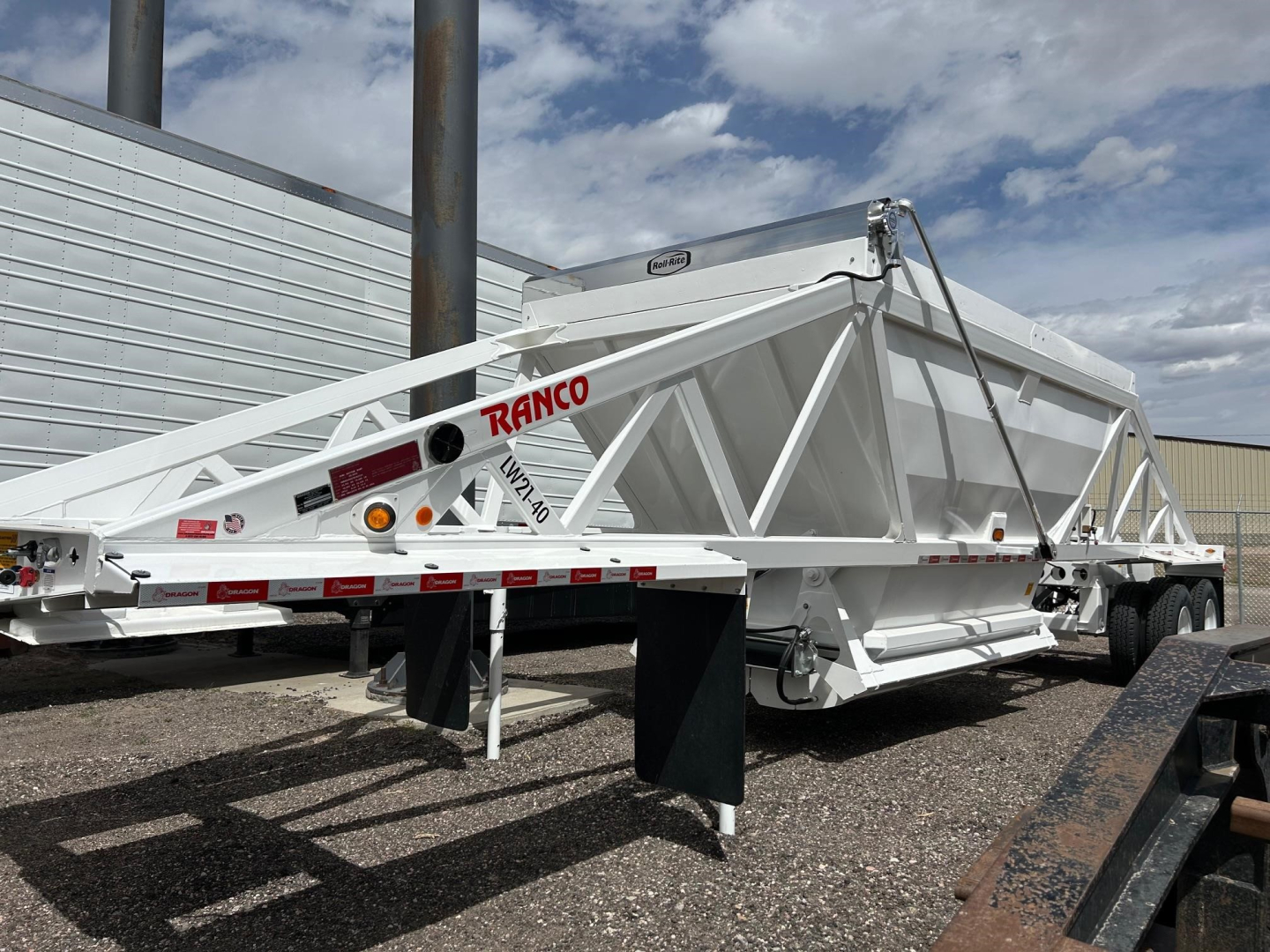 Bottom dump trailer showing white Ranco trailer with dual-axle layout and support legs extended.