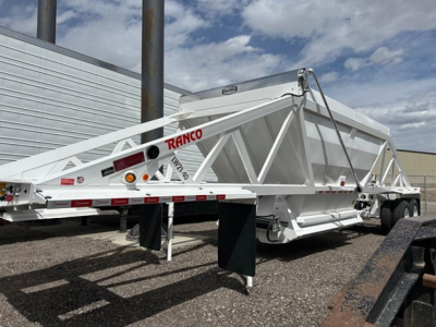 Ranco air ride bottom dump trailer in white, dual-axle with frame braces and hydraulic lift arms visible, side ramp support, brand name ‘RANCO’ on the frame.