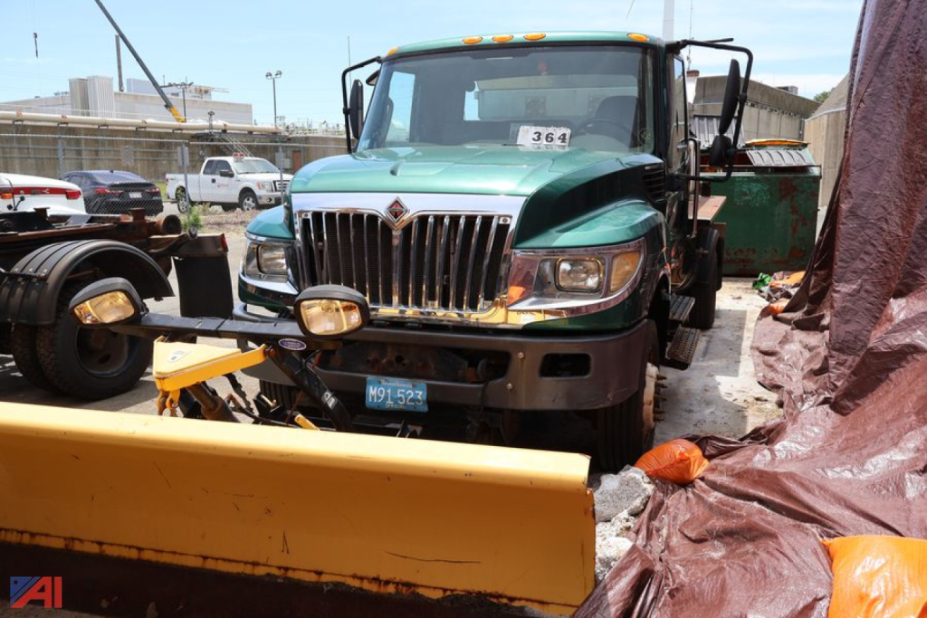 2015 International TerraStar truck with swaploader attachment in front, green cab, yellow plow blade, parking lot background.