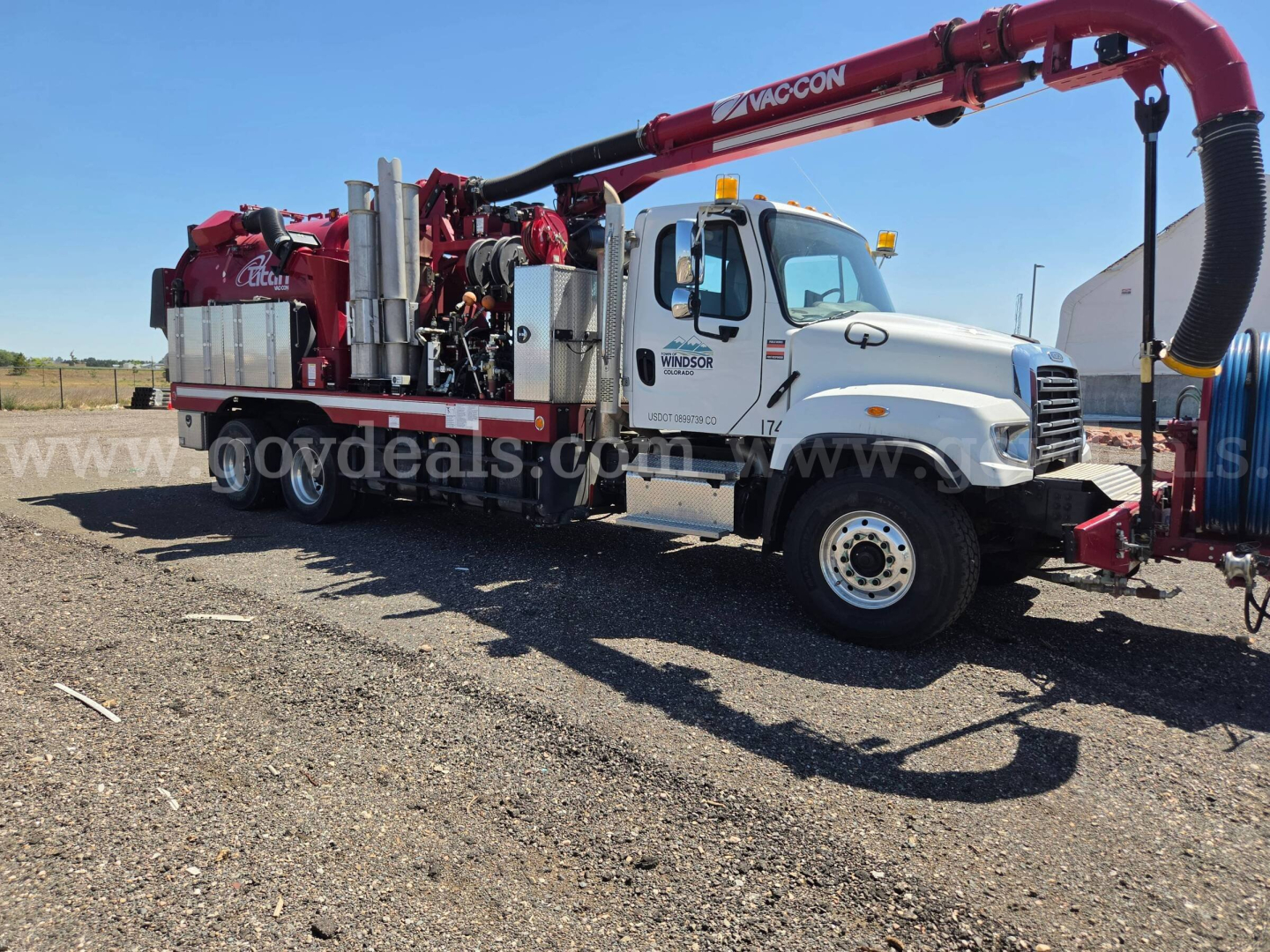 Truck with VacCon vacuum system mounted on a Freightliner 114SD chassis showing VacCon boom and equipment, side cab text and hose attachments.
