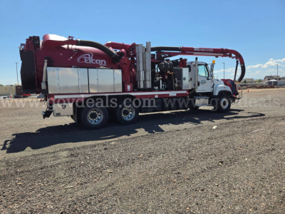 Freightliner 114SD vacuum truck with red Ricon vacuum system and white cab, side view showing long chassis and equipment hoses