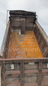 Dump truck bed interior showing rusted bed floor with orange residue and sidewalls; tailgate area with ‘ROGERS’ branding.