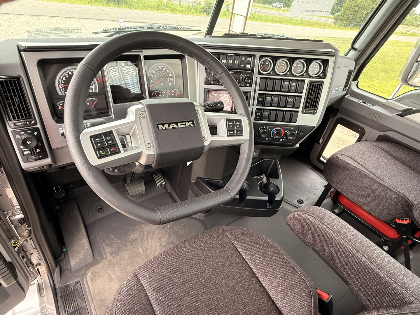 Mack PI64T cabin interior showing steering wheel, dashboard with gauges, control panels, and driver seat.