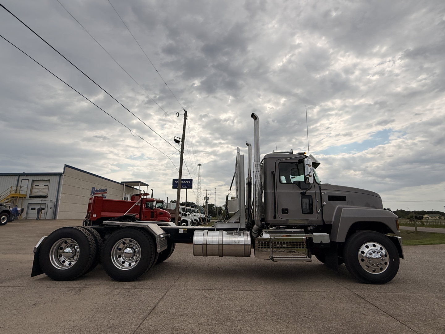 Mack PI64T conventional daycab truck side view showing chrome fuel tanks and exhaust stacks.