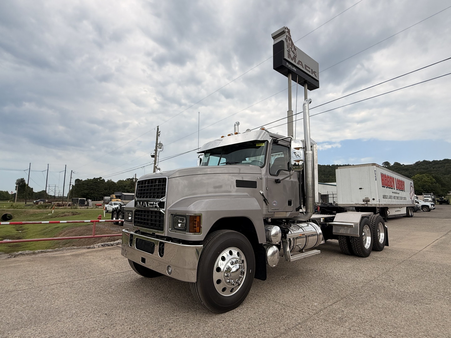 Mack PI64T truck in a dealership lot showing side profile and cab details with trailer attached