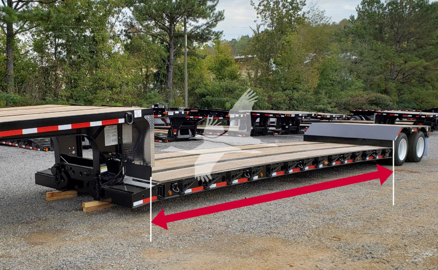 Fontaine Renegade trailer in yard showing long flatbed with red arrow overlays and white vertical markers.