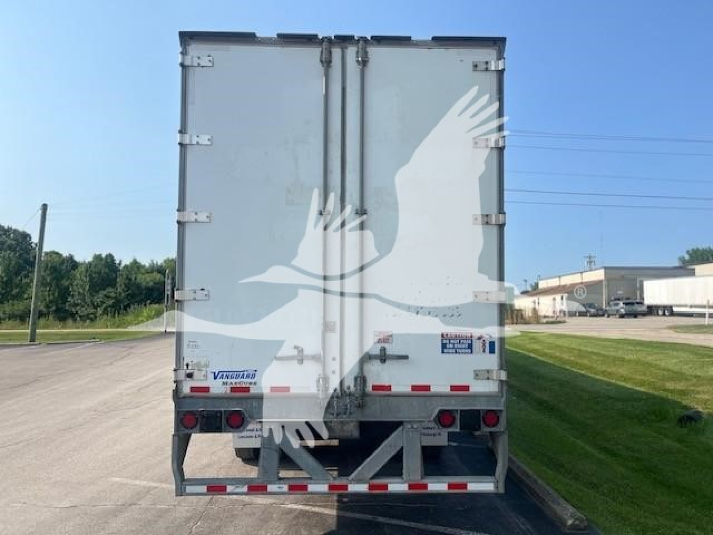 Vanguard Maxcube trailer rear view showing dual rear doors, taillights, and bumper; white with rear reflective strips.
