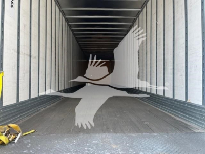 Trailer interior showing empty cargo space with metal ribbed walls and floor; open rear end; logo watermark visible.