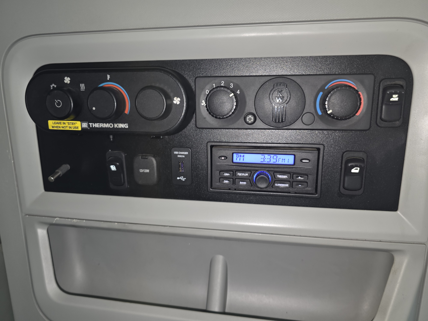 Kenworth T680 dash panel showing climate controls and radio, gauges, and knobs in cabin dash view.