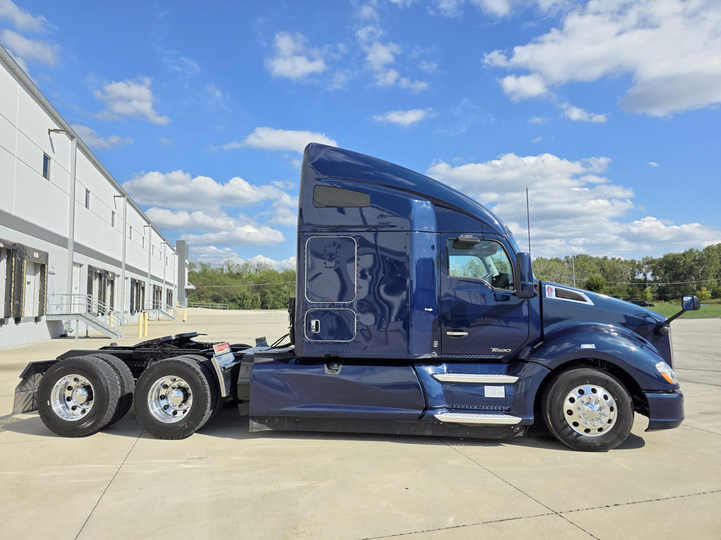 Kenworth T680 sleeper cab tractor in blue, side view, 6-wheel configuration, clear sky, no text visible on vehicle