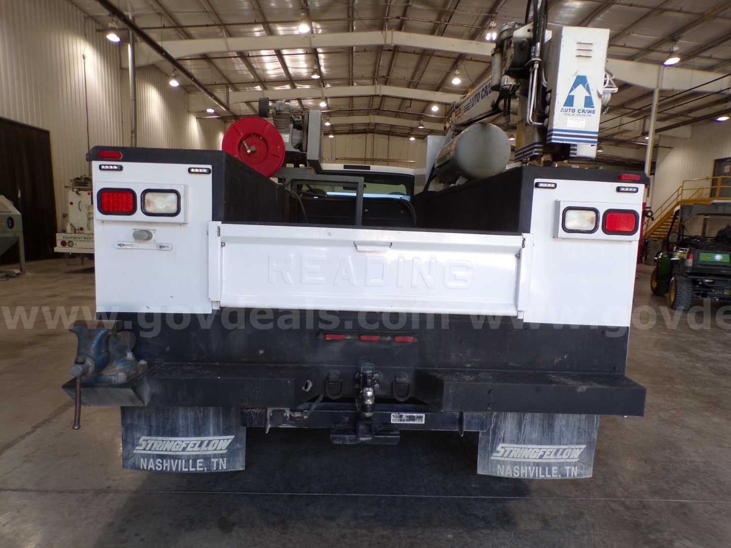 Truck bed of a service/utility truck in a warehouse showing rear assembly and tail lights.