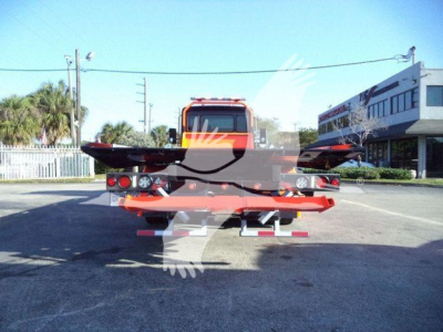 Truck bed with a rollback tow equipment on a 2025 Kenworth T280 chassis, rear view showing flatbed and wheel arches.