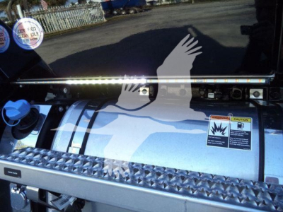 Kenworth T680/T-Series fuel tank area with diamond plate step, warning sticker, gas cap, and chrome rail