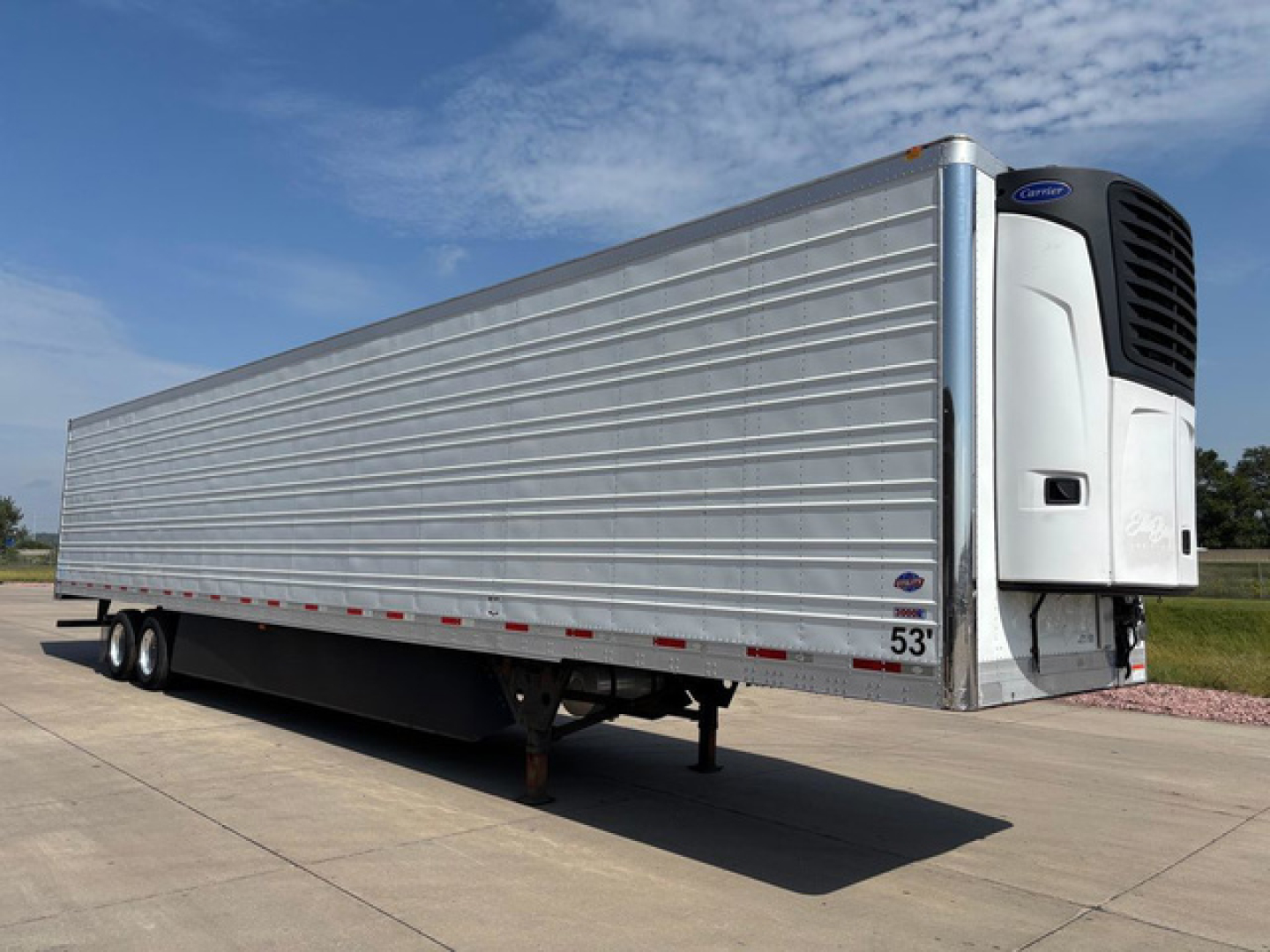 Refrigerated trailer in-service showing a white carrier unit and ribbed aluminum sides with a white cab at the front, 53' length, under clear blue sky.