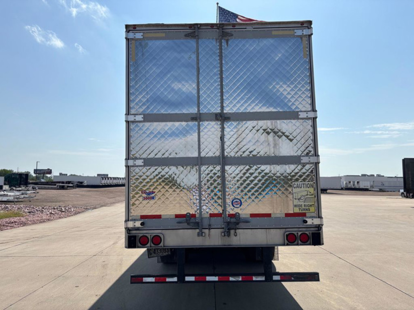 Rear view of a 2019 Utility reefer trailer with diamond plate doors, rear bumper, and taillights. Caution label and reflective strips on doors.