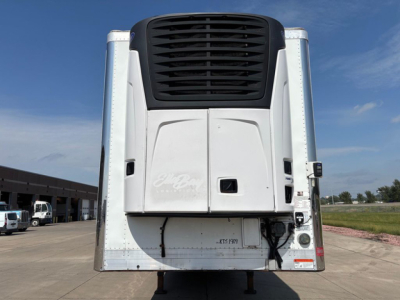 Reefer trailer back view showing white body with black cooling unit and vertical corners; no visible text other than subtle, unreadable decals.