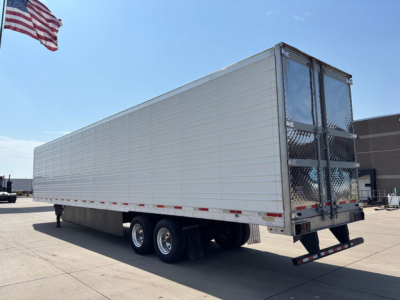 Utility reefer trailer with three-axle tandem showing side view and rear doors, aluminum exterior, ramps at back, American flag in top left.