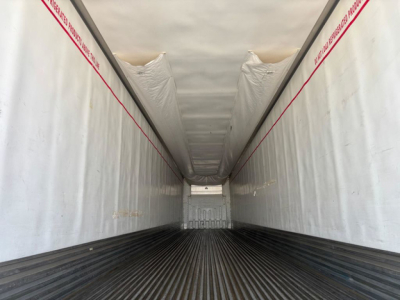 Trailer interior view showing corrugated metal floor and white insulated sidewalls with red warning stripes. Center back door open. Visible text on stripes: 'PRO...'.