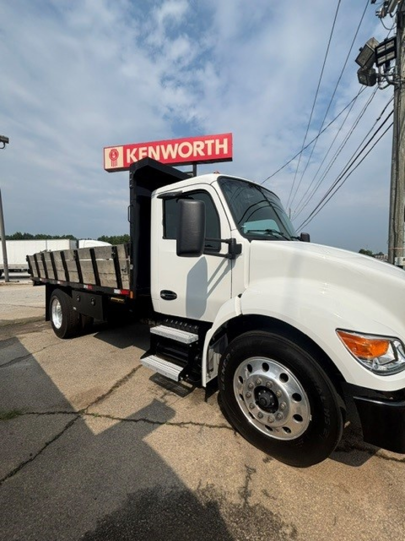 Kenworth T280 cab and chassis truck with white cab and flatbed, side steps, large front wheel, Kenworth sign in background.
