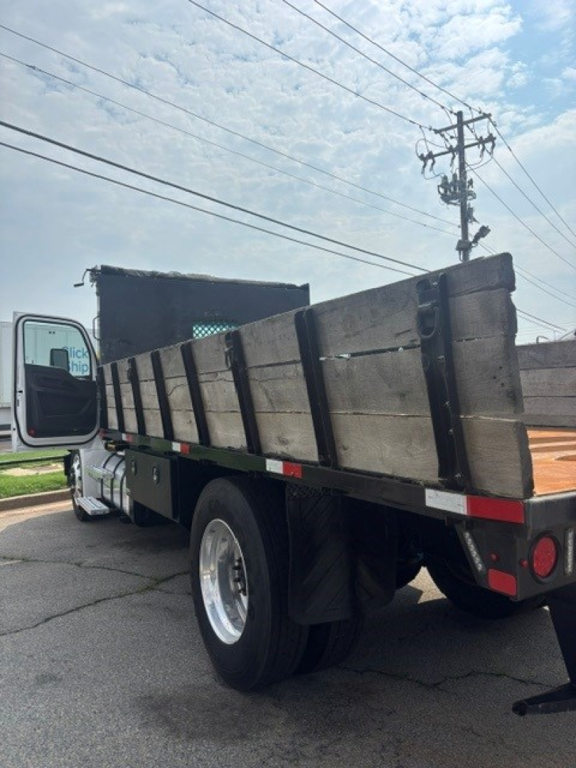 Kenworth T280 cab and chassis dump bed trailer visible from rear-left side showing wooden stake-sided flatbed and dual rear lights.