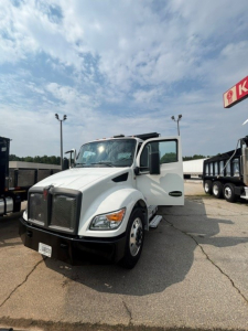 Kenworth T280 cab and chassis truck with open driver door showing front grille and headlights. Vehicle has white body, black bumper, and dual side mirrors in a dealership lot.
