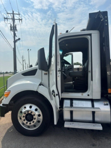 Kenworth T280 cab and chassis side view showing open driver door and steps, front wheel, and black crane or equipment mount behind cab.