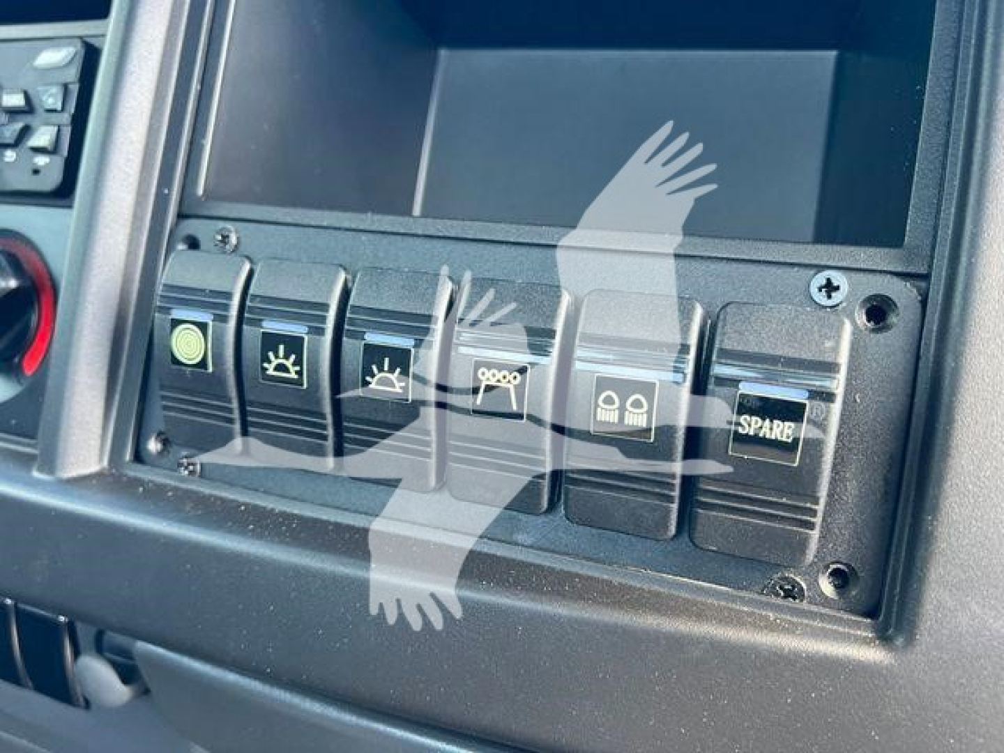 Isuzu NPRR dashboard switches with multiple icons and blank display screen in view showing control panel and buttons.