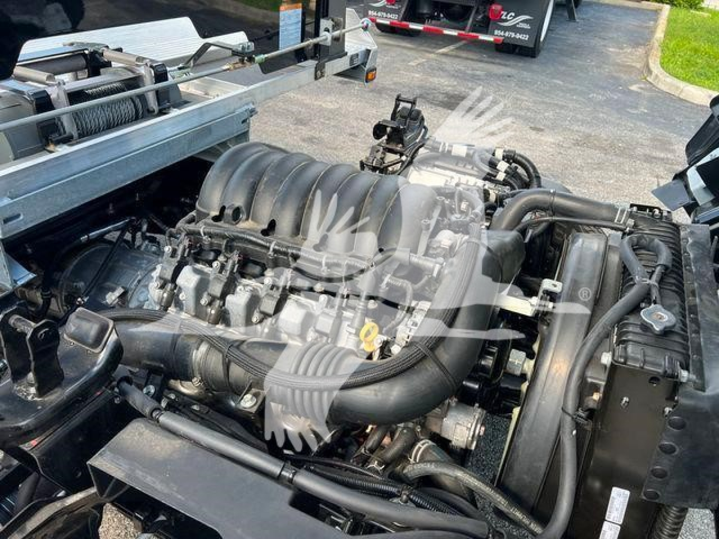 Isuzu NPR engine bay with large V8-like intake manifold visible; hoses, belts, and radiator nearby.