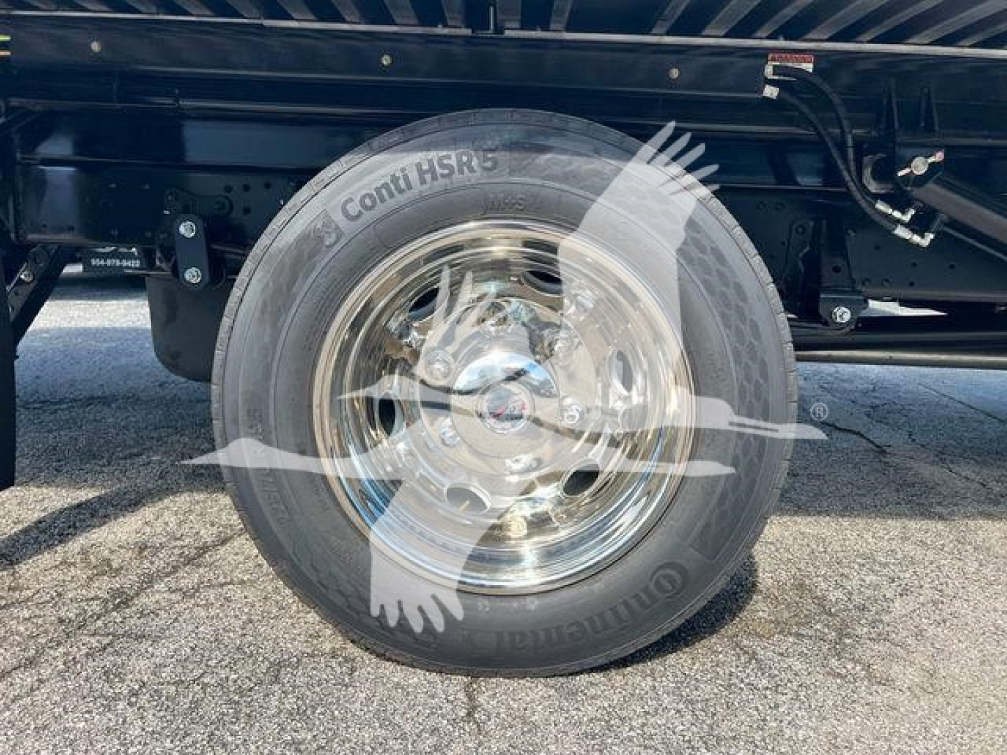 Isuzu NPRR wheel and tire on rollback truck showing Conti HSR5 tire, chrome rim, undercarriage with frame and suspension components visible.