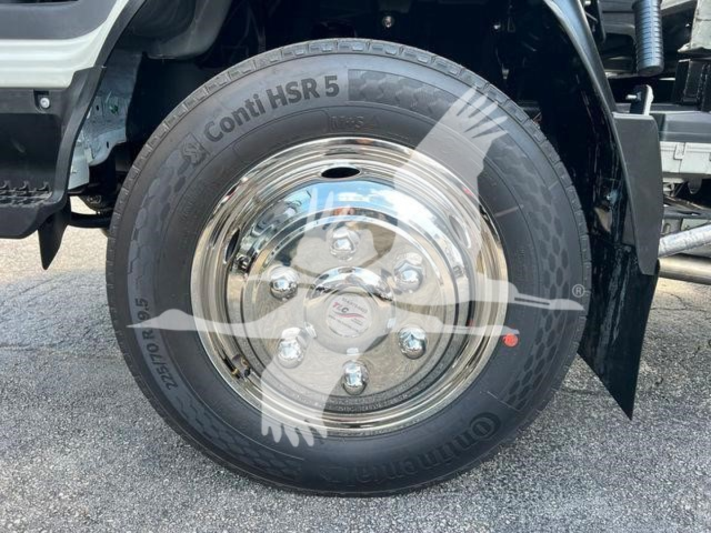 Truck wheel and tire on Isuzu NR R rollback showing Conti HSR 5 tire and polished steel rim with lug nuts.