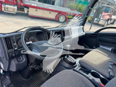 Isuzu NPRR truck cabin interior showing steering wheel, dashboard, driver seat with seatbelt, center console, gear shifter, and cup holders.
