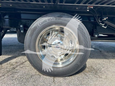 Isuzu NPRR wheel and tire on rollback truck showing Conti HSR5 tire, chrome rim, undercarriage with frame and suspension components visible.