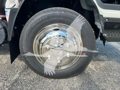 Truck wheel and tire on Isuzu NRR rollback showing 225/70 R19.5 tire and chrome hubcap.