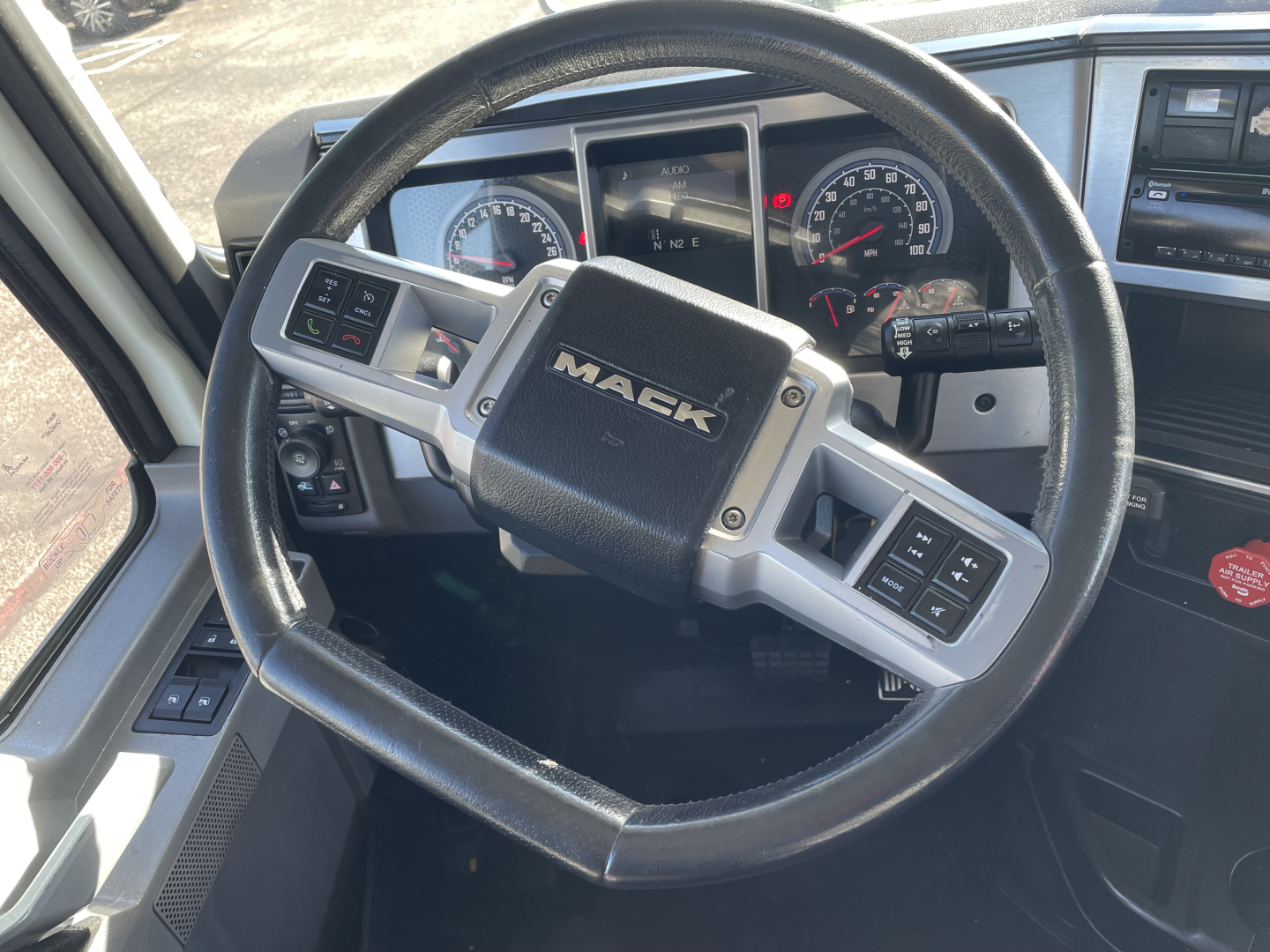 Steering wheel view inside a 2020 Mack AN64T truck cab showing Mack logo, instrument cluster, and steering wheel controls.