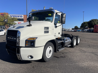 Mack AN64T conventional daycab truck in a truck lot, white, front-left view showing Mack grille and dual rear axles.