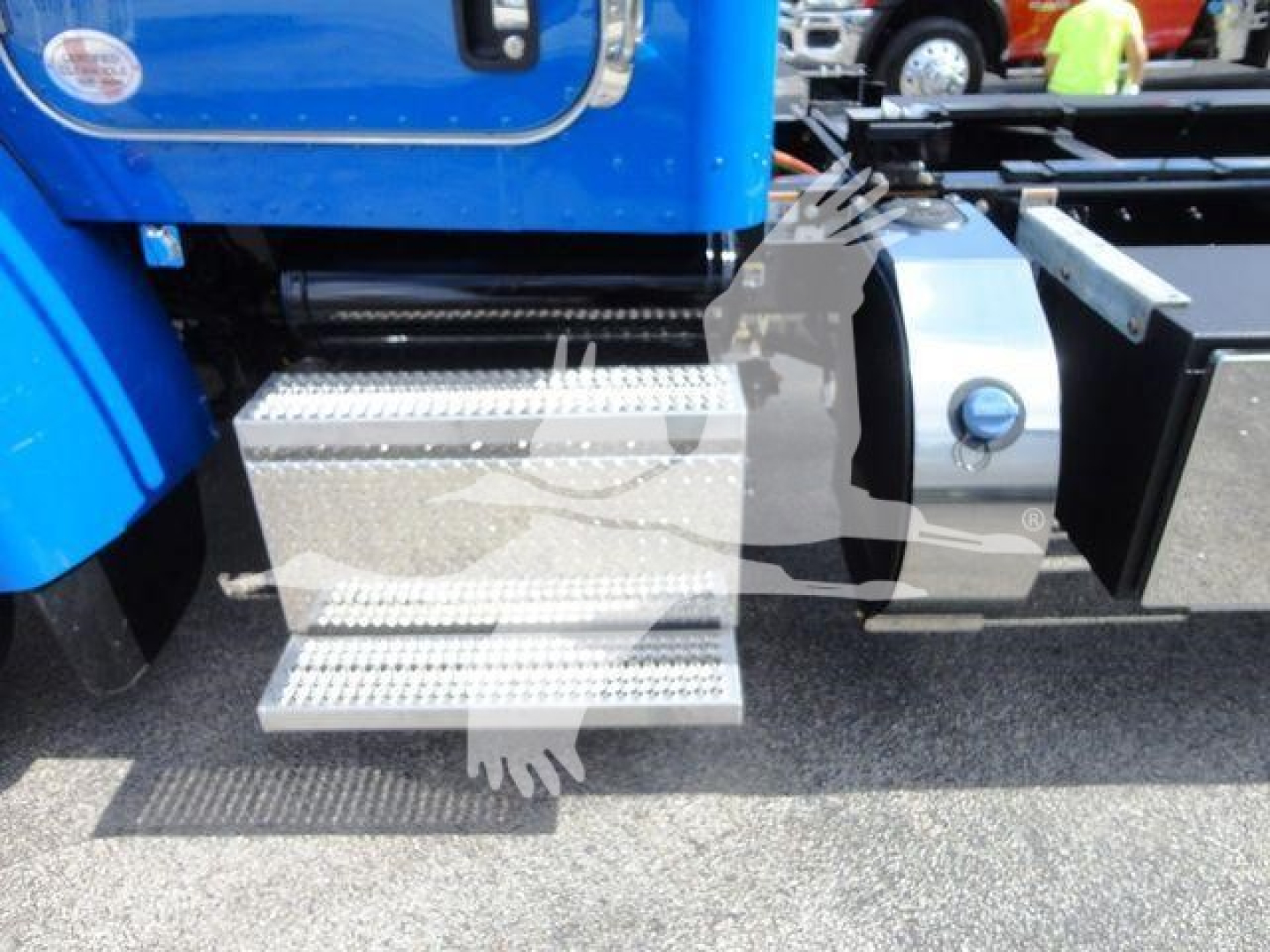 Truck side view showing metal steps and blue cab of a 2022 Peterbilt 337 rollback truck with chrome toolboxes and side steps.