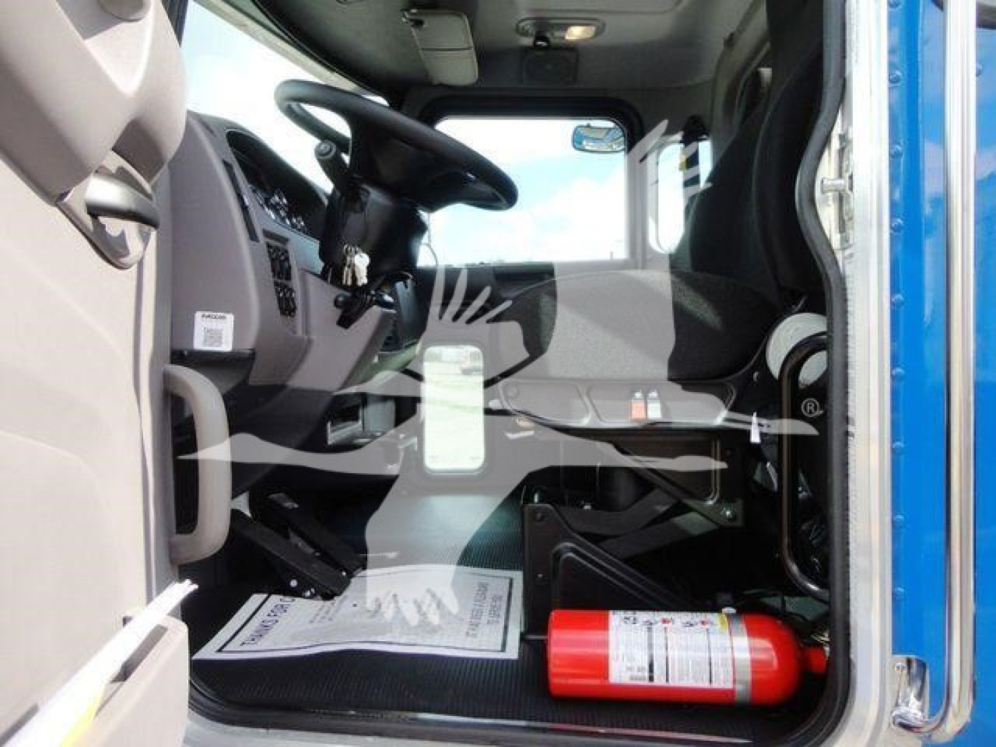 Truck cab interior view of a 2022 Peterbilt 337 Rollback with driver seat, steering wheel, dashboard, and a red fire extinguisher visible on the floor.