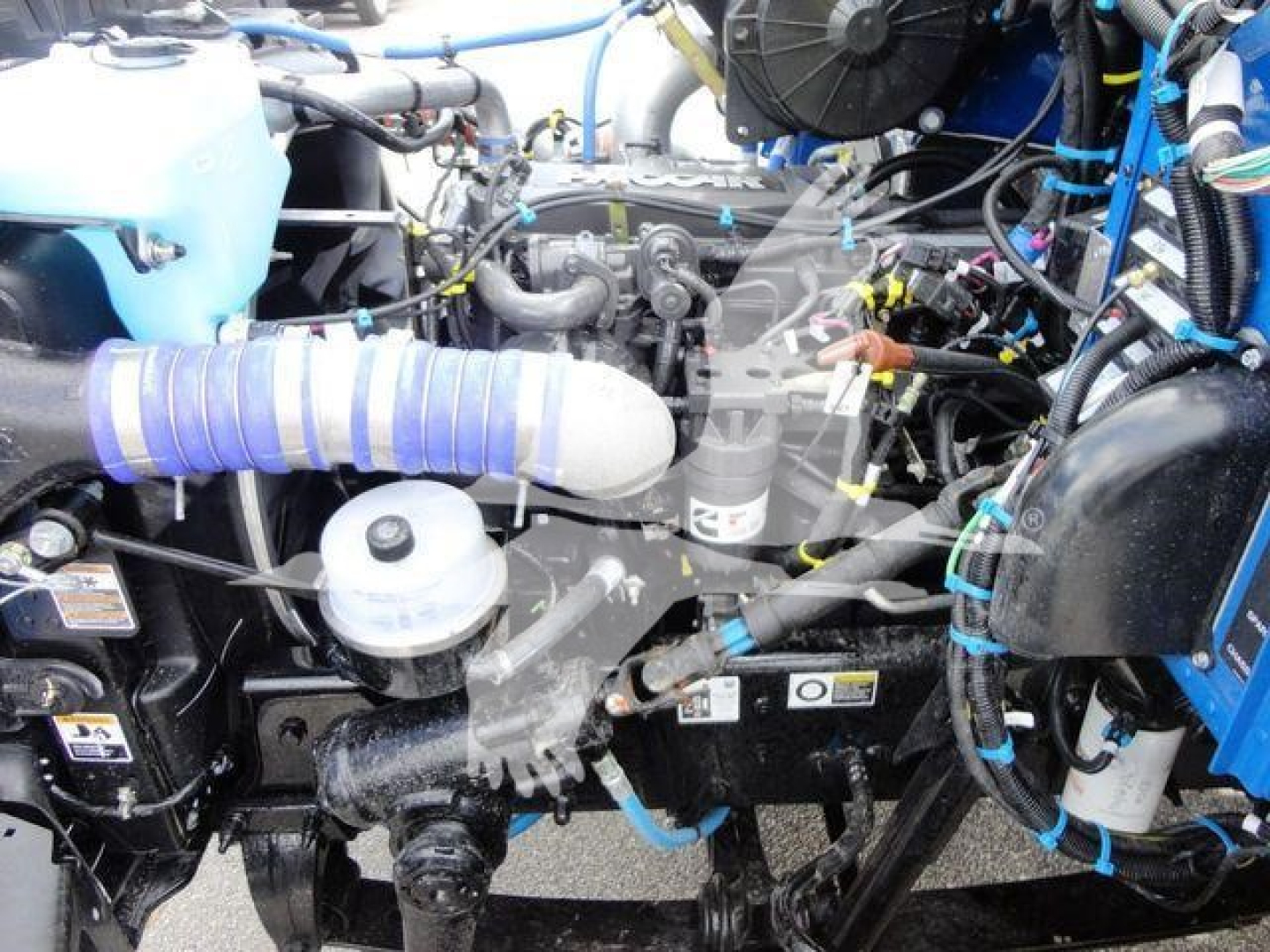 Peterbilt 337 engine bay showing service components including air intake hose, coolant reservoir, hoses, wiring, and engine block.