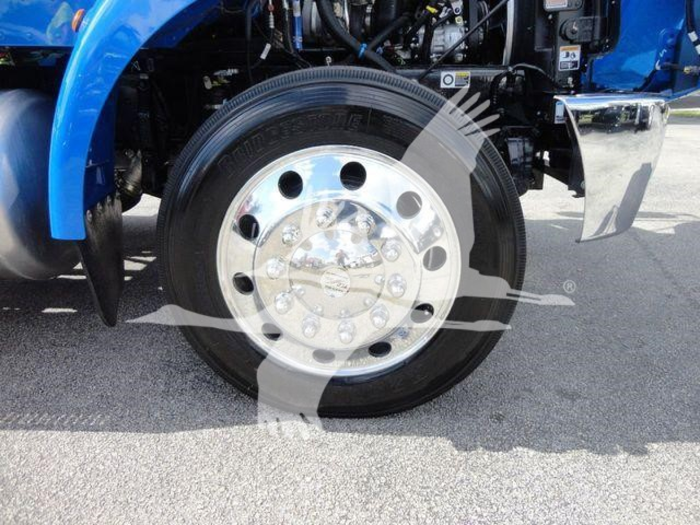 Peterbilt 337 front wheel showing polished aluminum hub with circular lug nuts and black tire.
