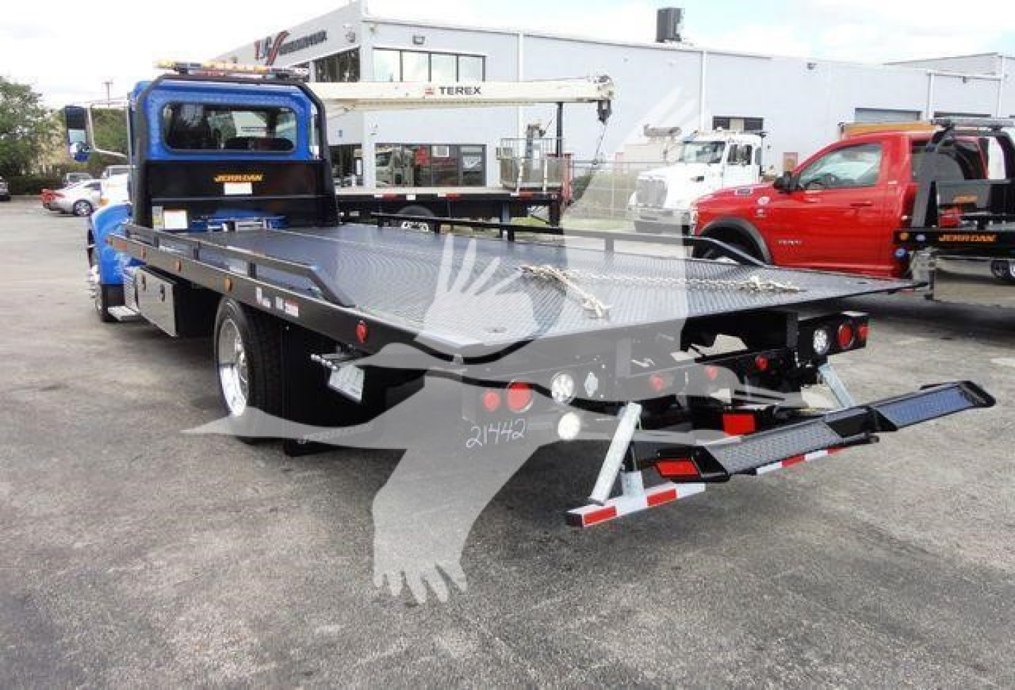 Peterbilt 337 rollback truck flatbed with loading ramps and crane in yard.