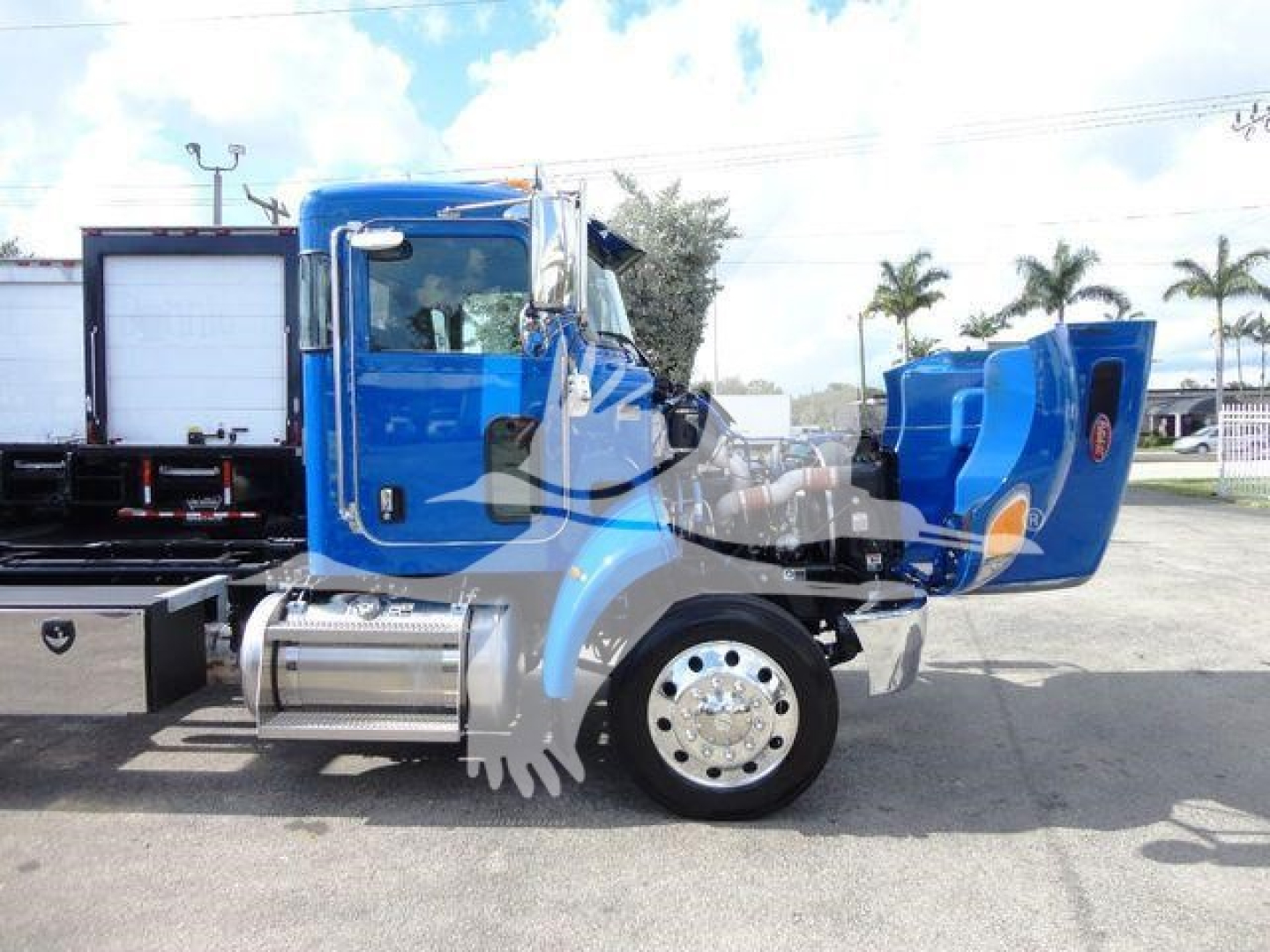 Peterbilt 337 rollback truck in blue with rear bed extended and chrome fuel tanks, side view showing cab and wheel with polished hubcap.