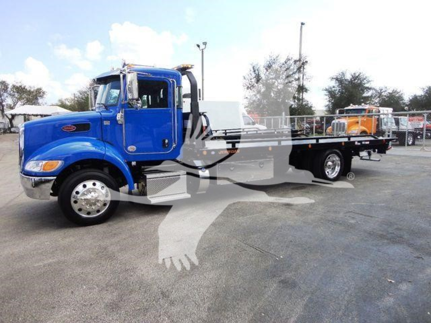 Peterbilt 337 rollback truck in blue, side view showing long flatbed and chrome wheels.