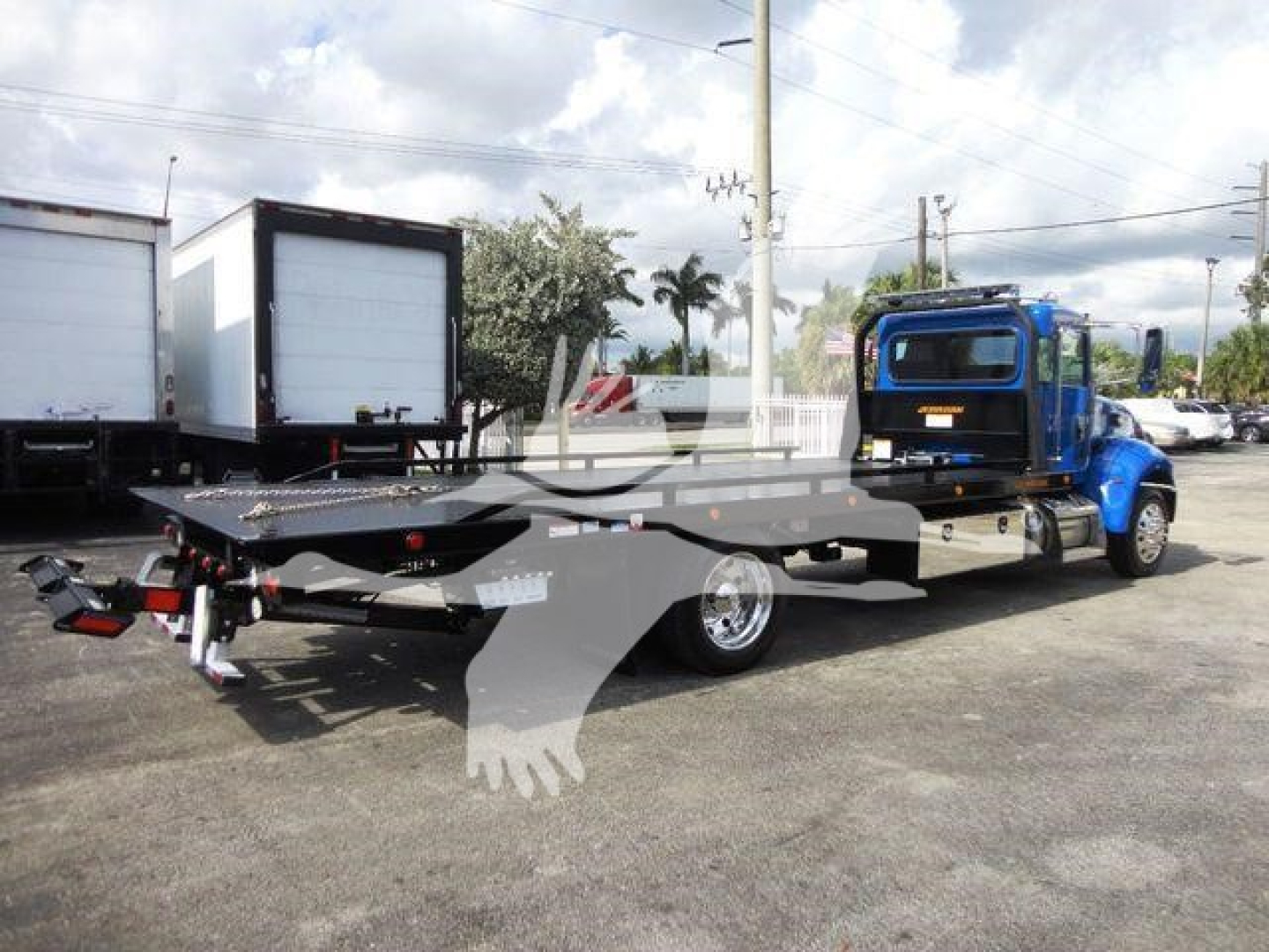 Peterbilt 337 rollback tractor shows blue cab and long flatbed with wheel lift, side mirrors, and chrome features.