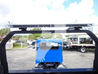 2022 Peterbilt 337 truck cab view with rollback setup in background showing a blue cab, overhead light bars, and trailer in lot.