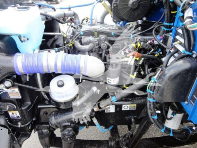 Peterbilt 337 engine bay showing service components including air intake hose, coolant reservoir, hoses, wiring, and engine block.